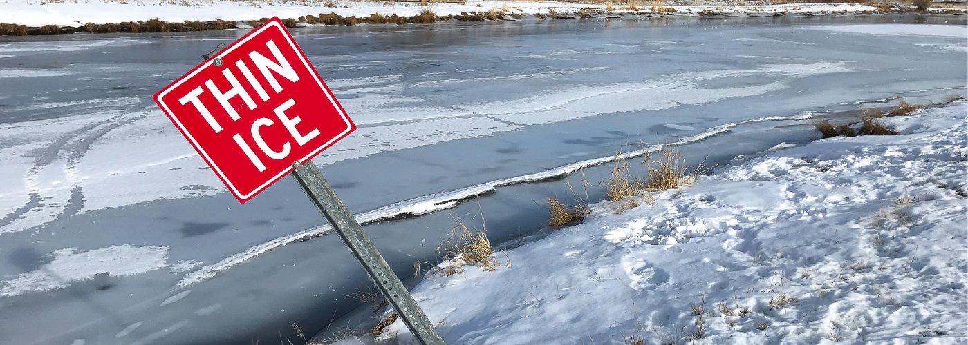 Image of a frozen over waterway with a sign saying Thin Ice